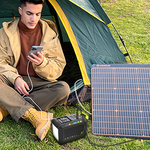 Mann benutzt ein tragbares Solarpanel in einem Zelt